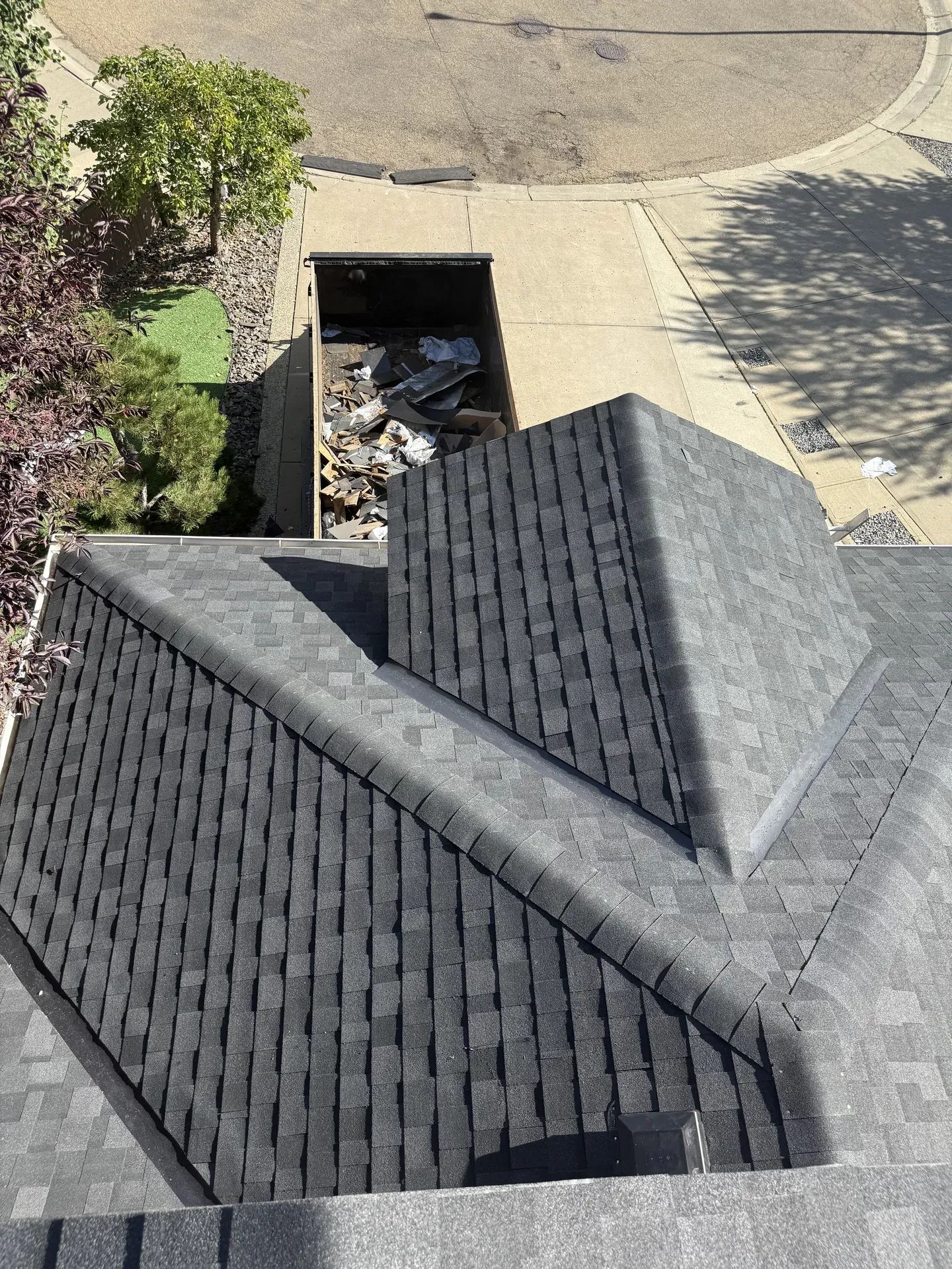 Aerial view of a roof tear-off with dumpster below