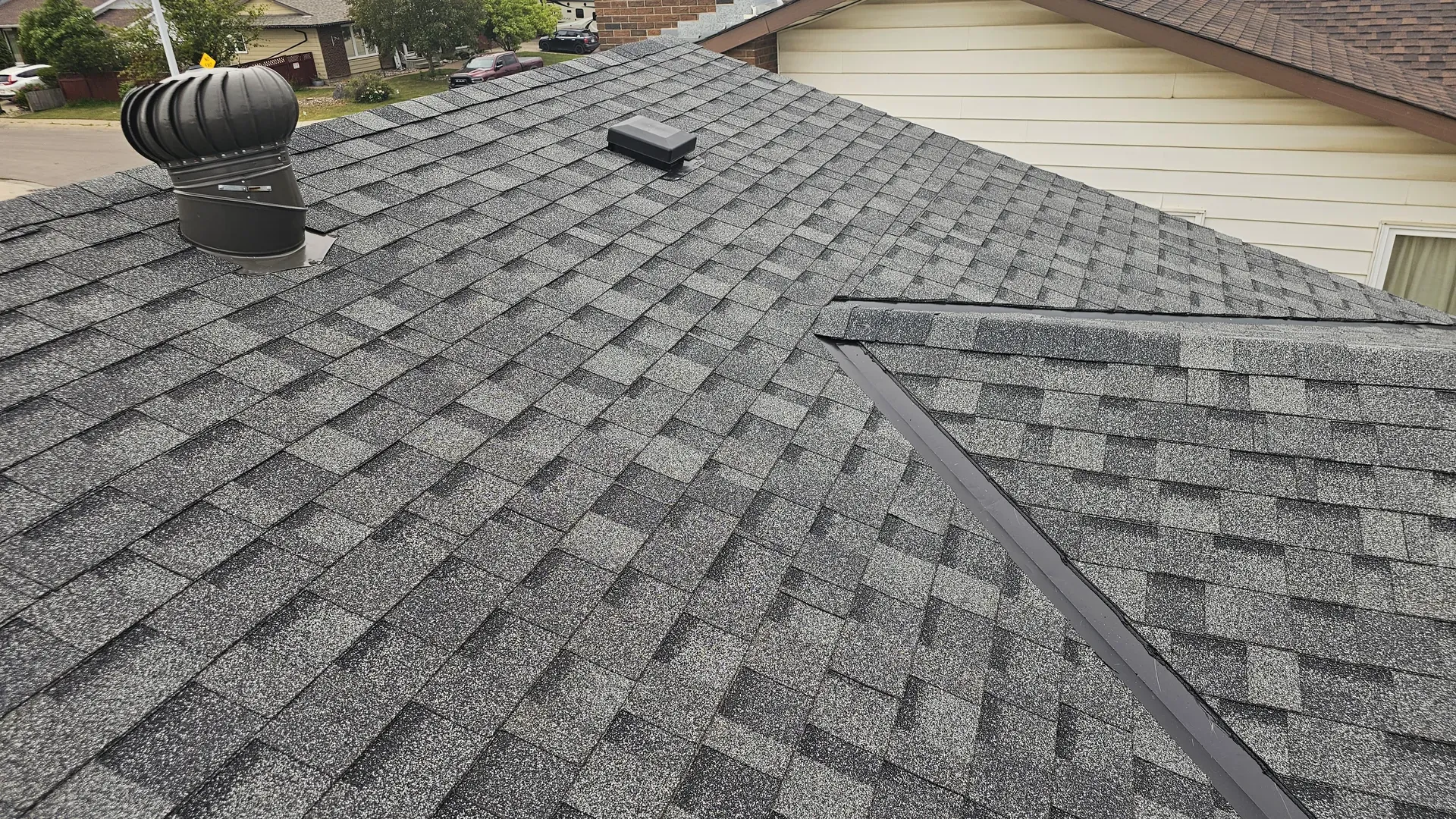 Gray architectural shingles with turbine vent at golden hour